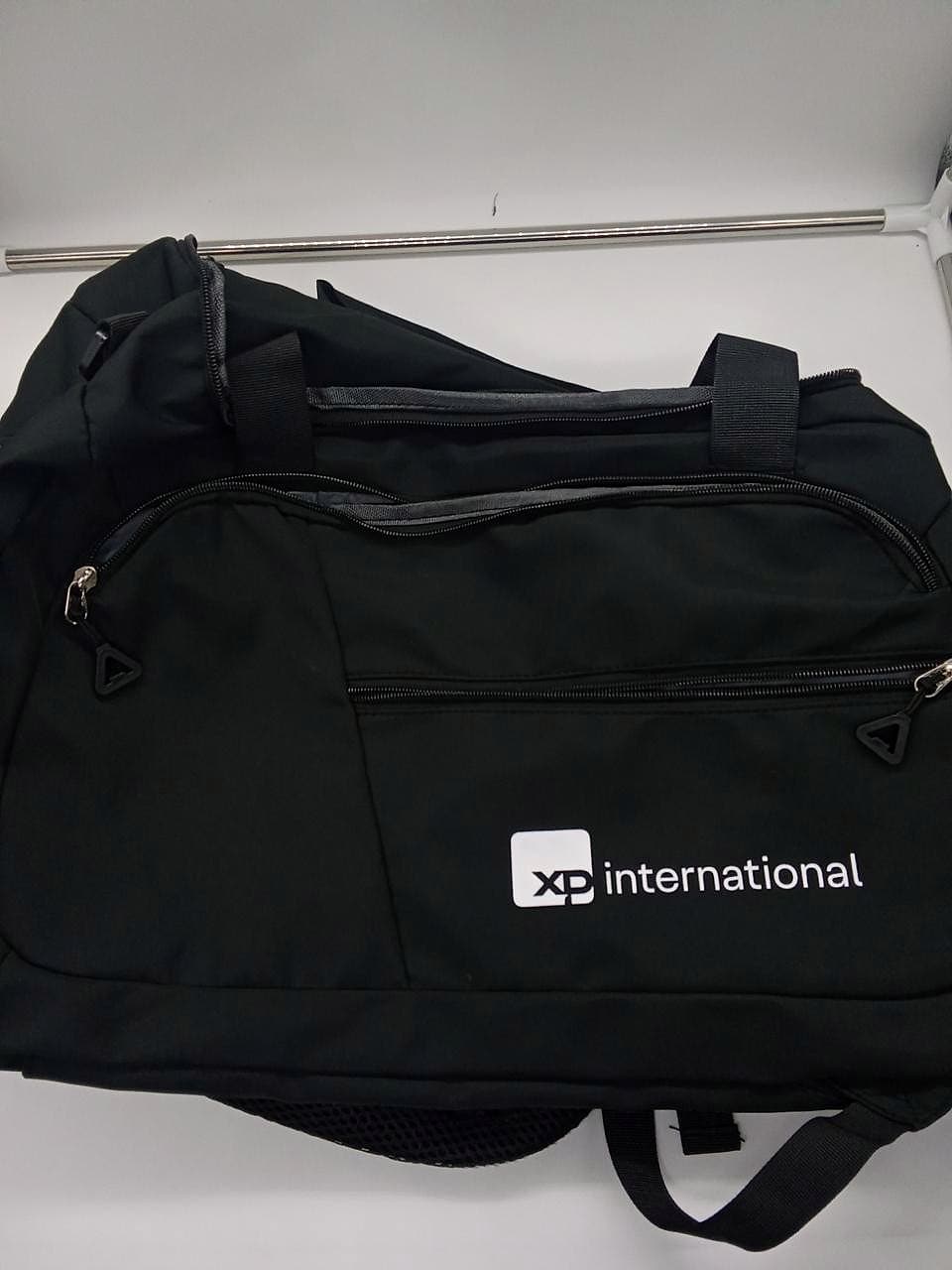 Bolsa de viagem preta com logo XP International em branco.