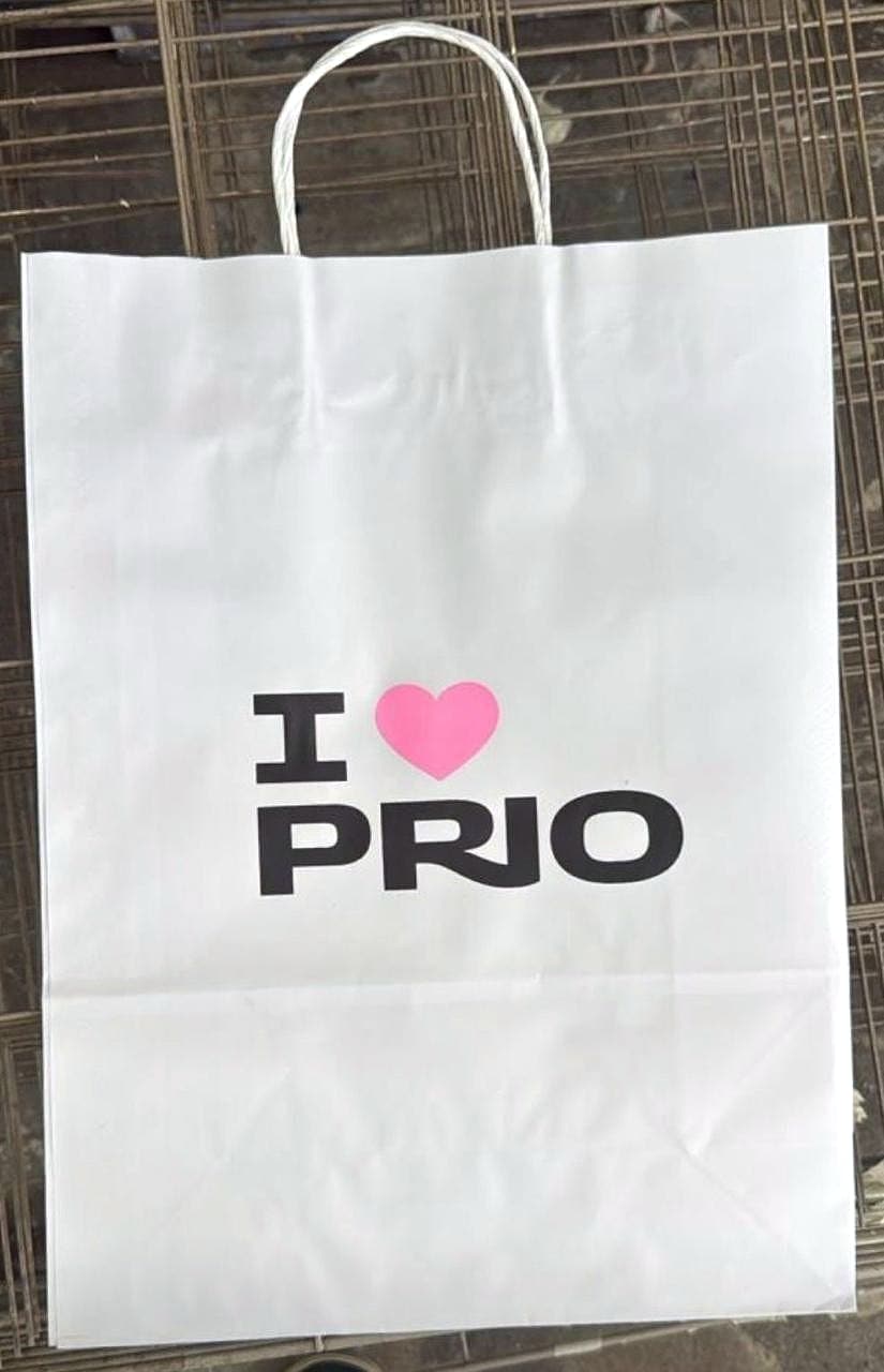 Sacola de papel branca com alças torcidas e a impressão 'I ♥ PRIO' em preto e rosa.